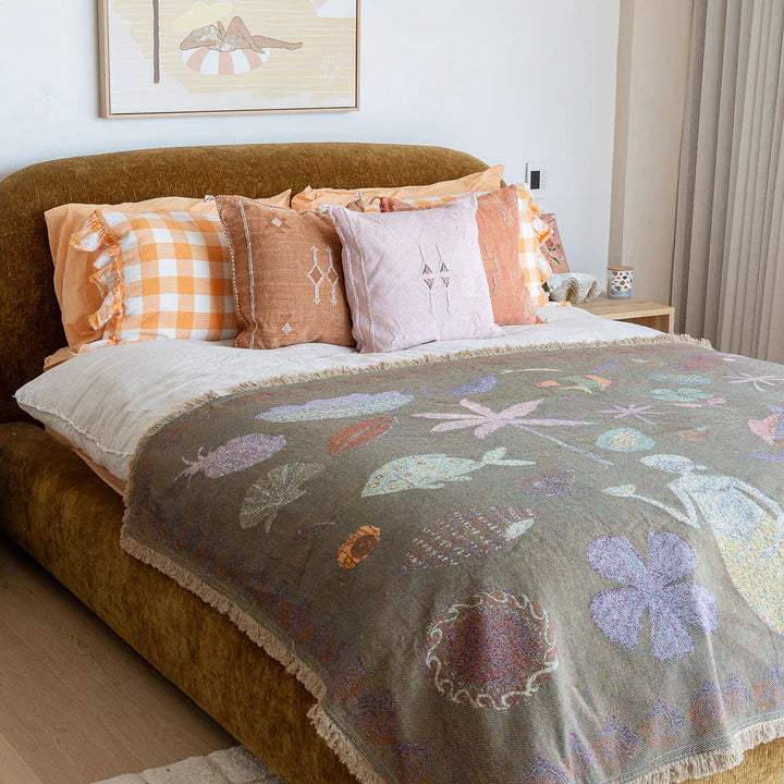 Bedroom with a bed featuring a floral blanket and colorful pillows, with a painting on the wall.