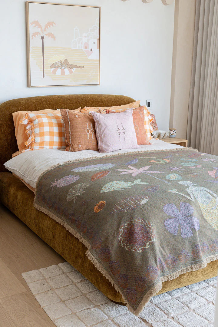 Bedroom with a bed featuring a floral blanket and colorful pillows, with a painting on the wall.
