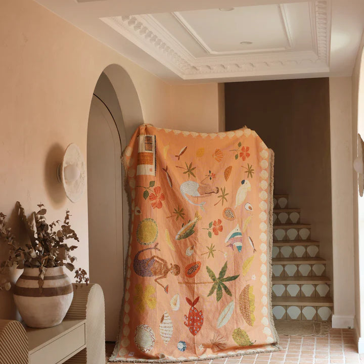 Decorative blanket with colorful patterns draped over a chair in a room with a tiled floor and decorative wall.