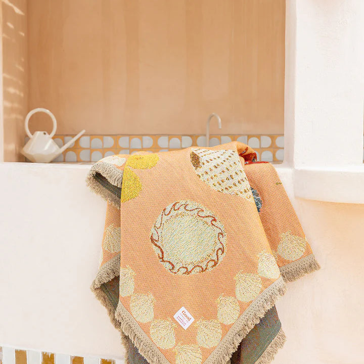 Decorative throw blanket with geometric pattern on a couch in a cozy living room.