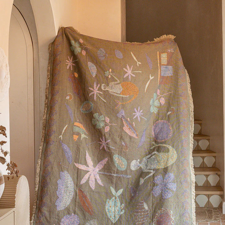 Decorative blanket with floral patterns draped over a chair in a room.