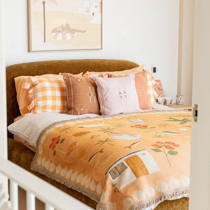 Bed with floral bedding and checkered pillows in a bedroom setting.