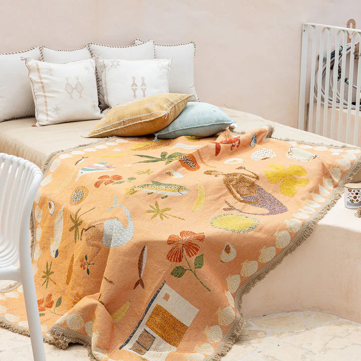 Children's room with a bed covered by a colorful blanket featuring cartoon animals.