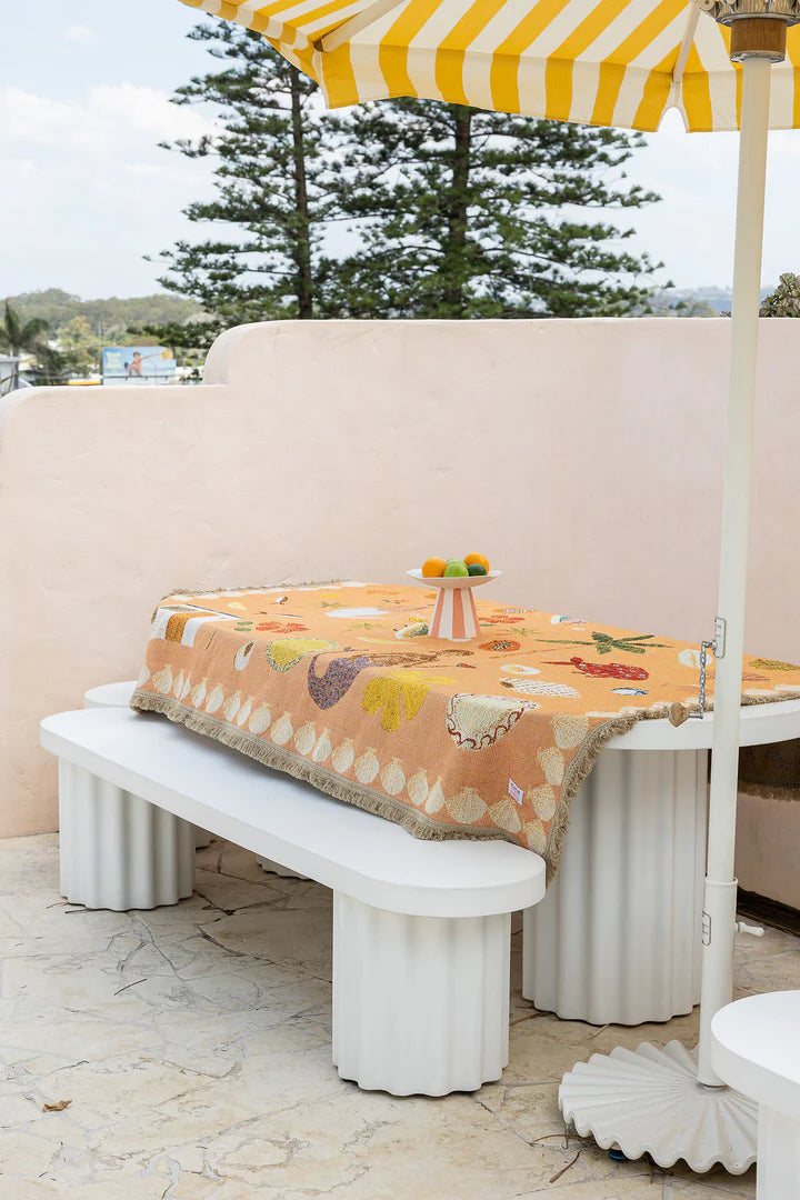 Outdoor setting with a table, bench, and striped umbrella on a patio.