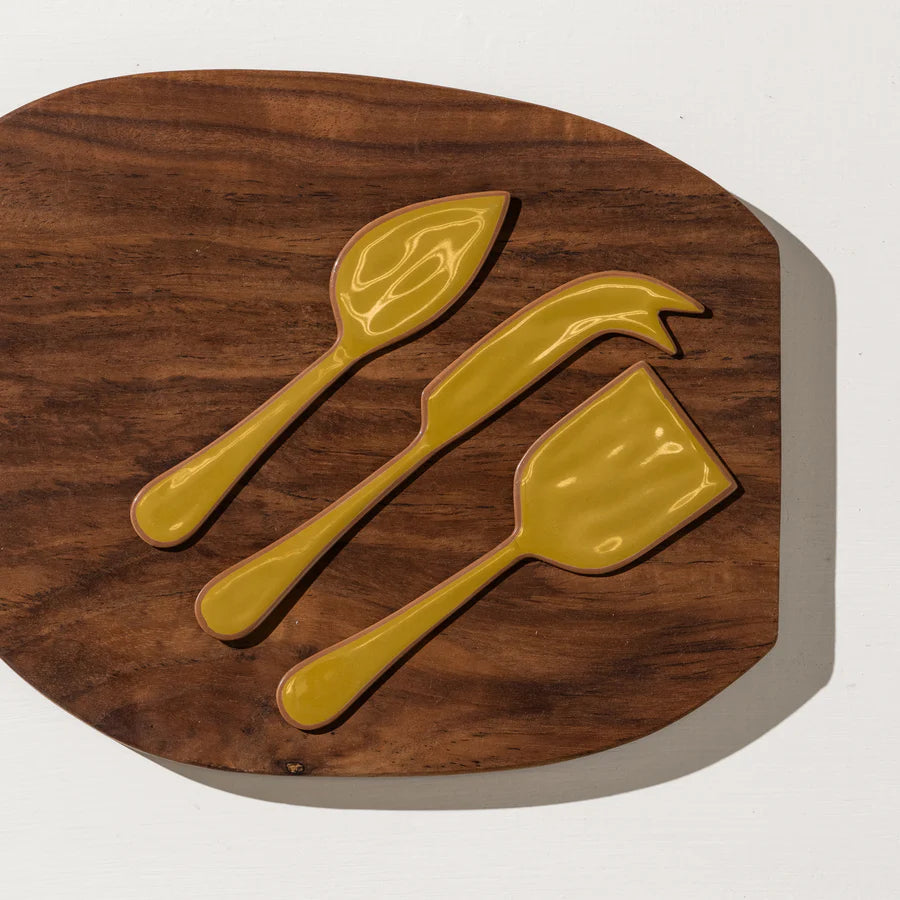 Three yellow ceramic spoons on a wooden cutting board
