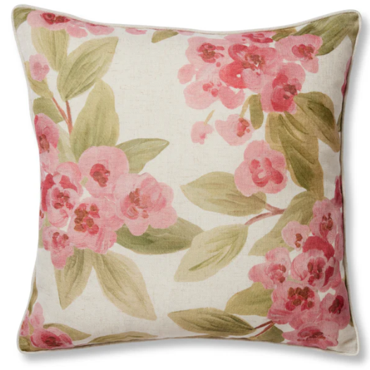 A square decorative throw pillow featuring a watercolor-style floral print of pink blossoms and green leaves on a cream linen-textured background.