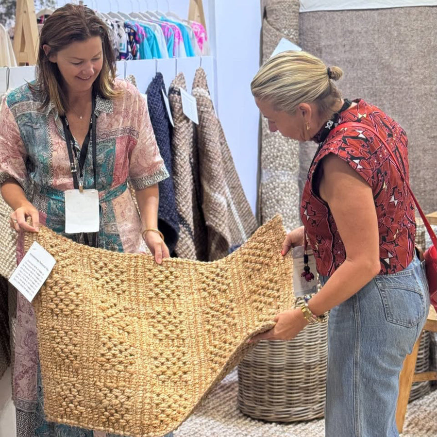 Two women examining a woven basket at an outdoor market.