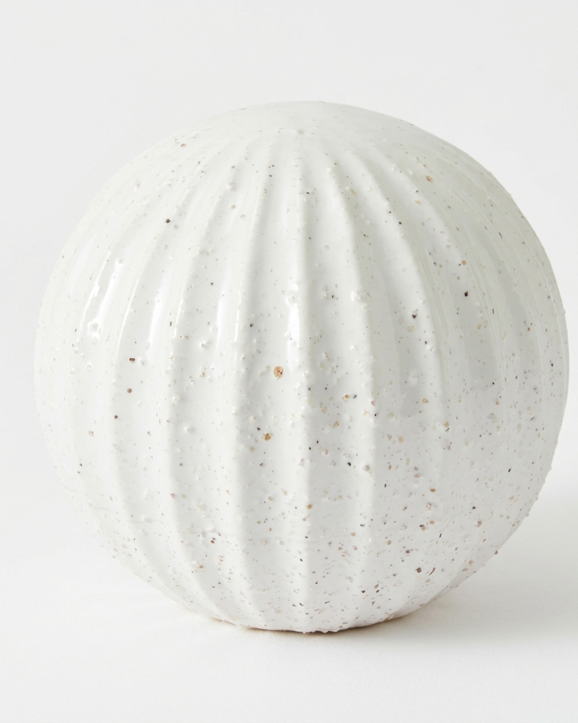 A round, ribbed ceramic vase in a speckled off-white glaze, photographed against a seamless white background.