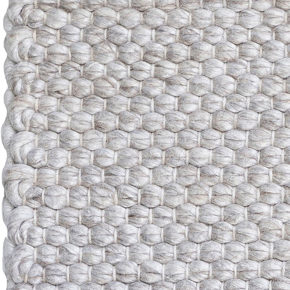 Close-up of a textured woven rug with a geometric pattern.