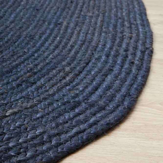 Close-up of a dark blue braided rug on a wooden floor