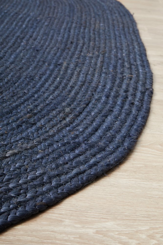 Close-up of a dark blue braided rug on a wooden floor