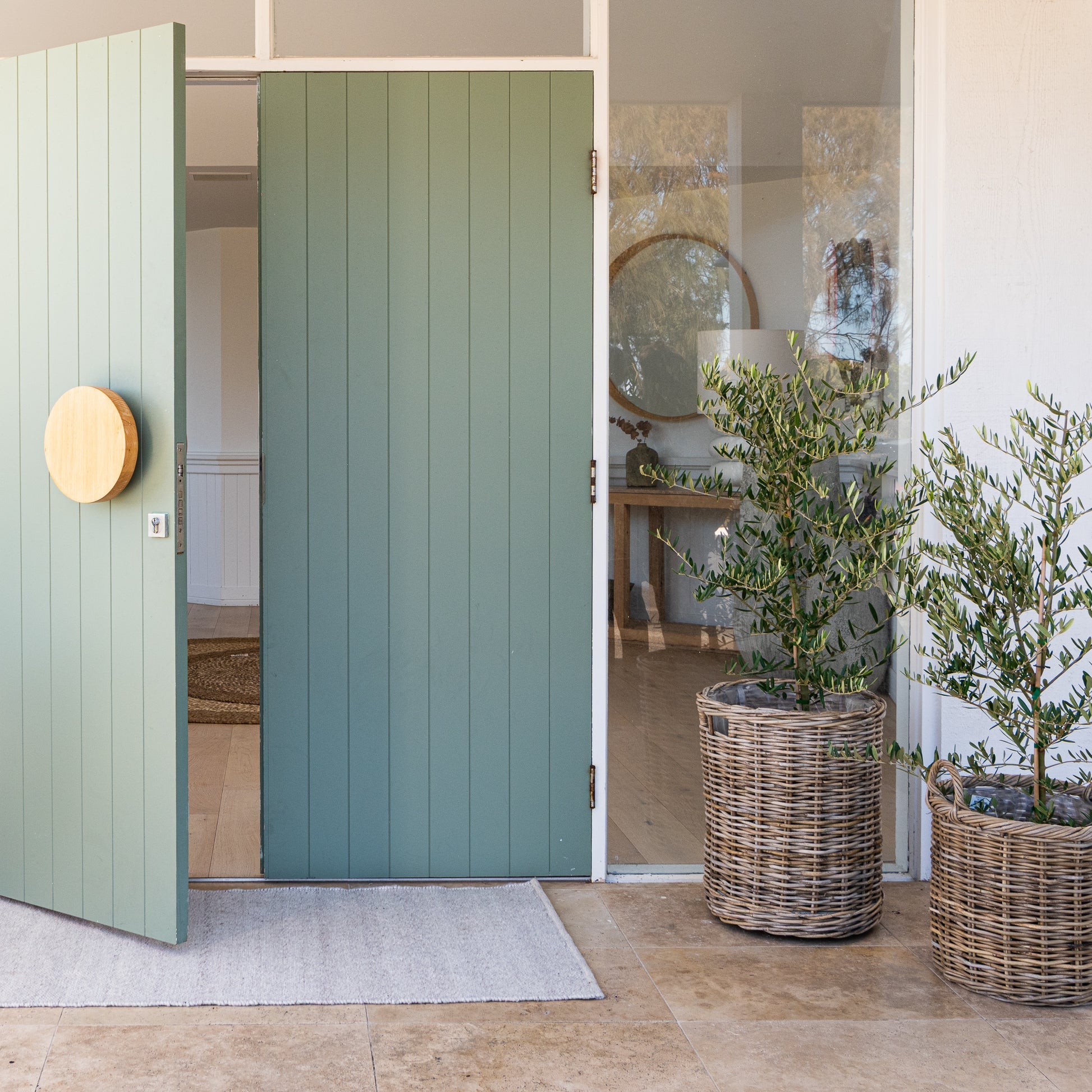 Green sliding door with wicker planters on a patio
