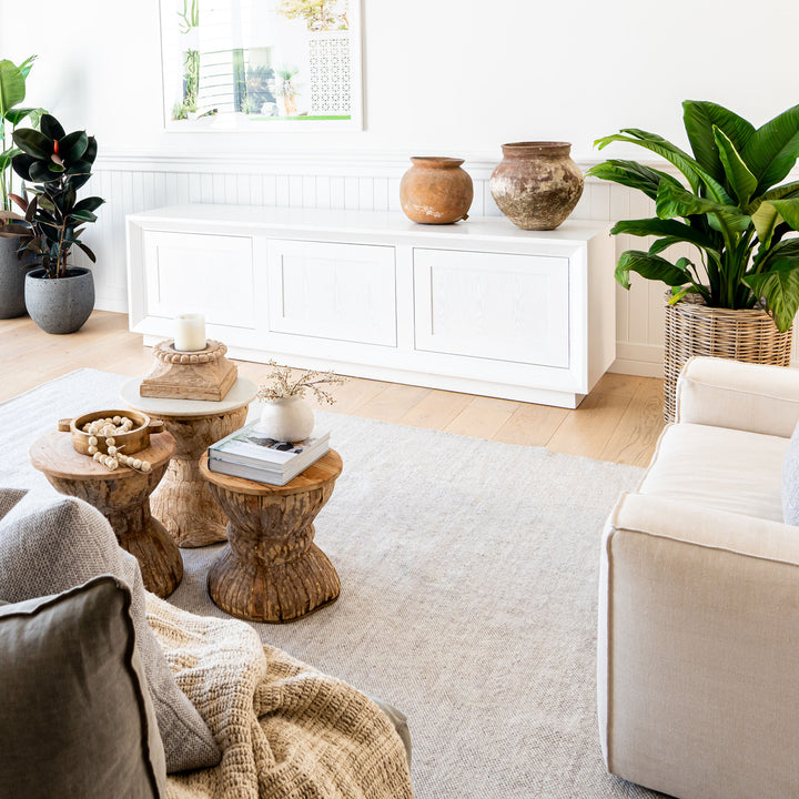 Living room with wooden coffee tables, white sofa, and decorative items.