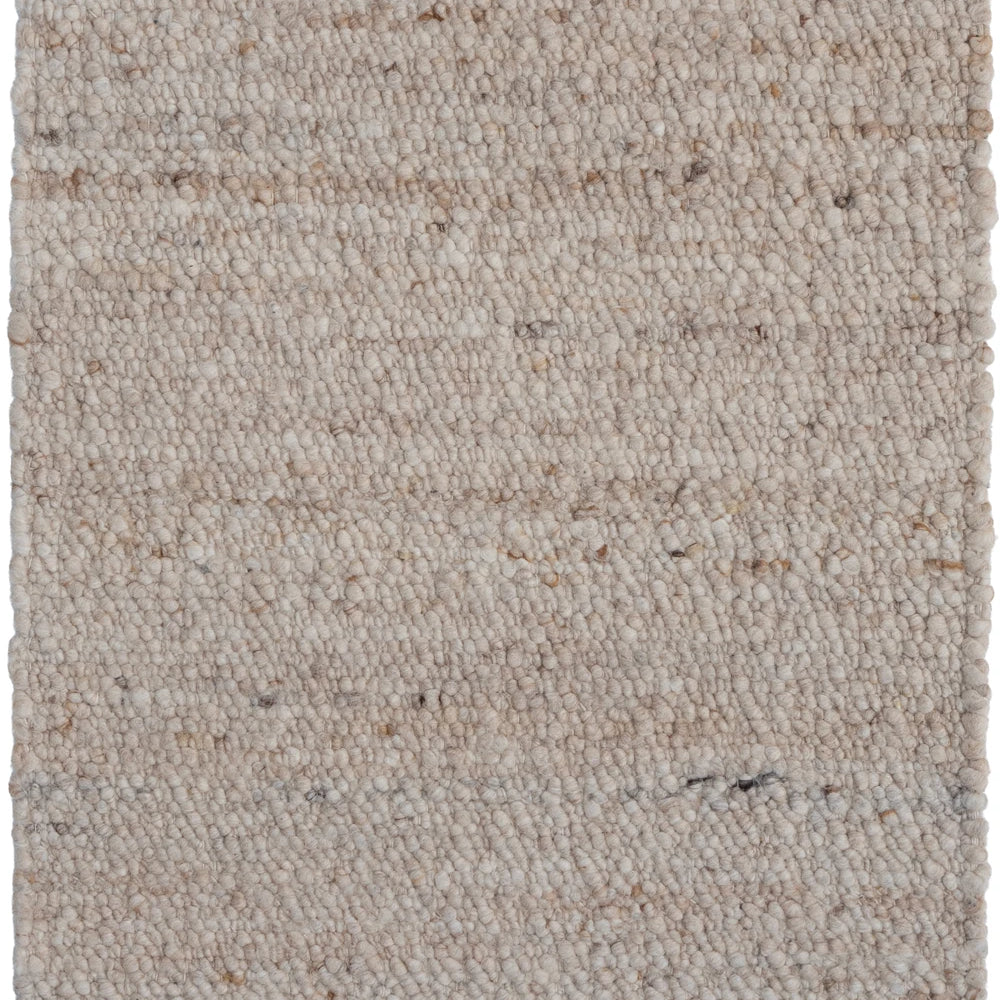 Textured beige rug with a subtle pattern on a plain background