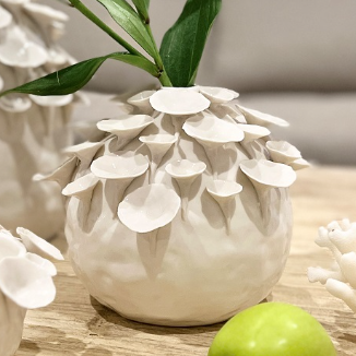 Decorative white ceramic vase with leaf design on a wooden surface