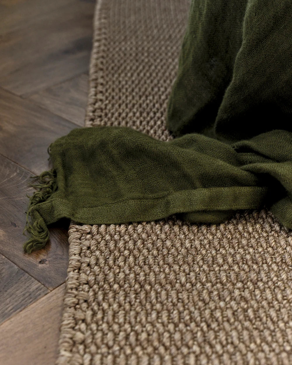 Green fabric draped over a textured rug on a wooden floor