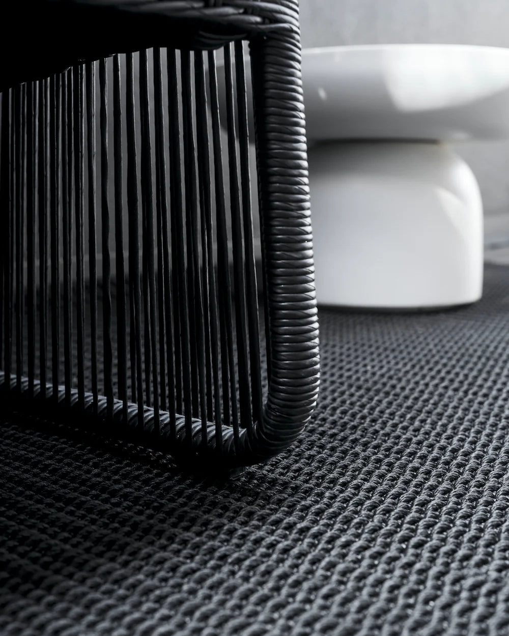 Close-up of a textured black surface with a white object in the background
