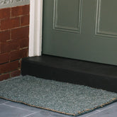 Green doormat in front of a green door on a brick wall background