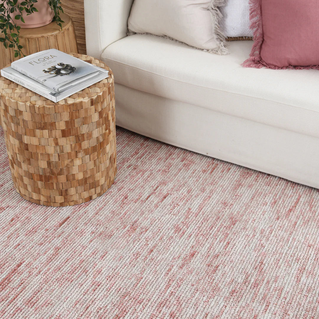 Living room with a beige sofa, wooden side table, and pink textured rug.
