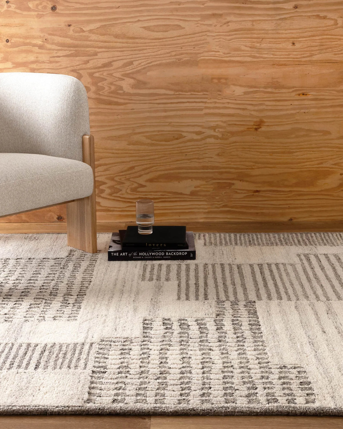 Rug with geometric pattern in a room with wooden wall and chair.