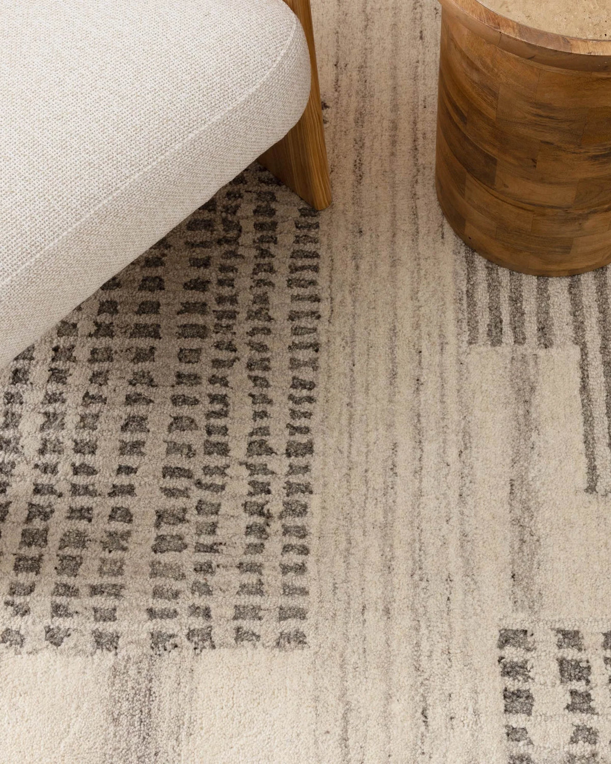 Patterned rug with a chair and wooden side table on a neutral background