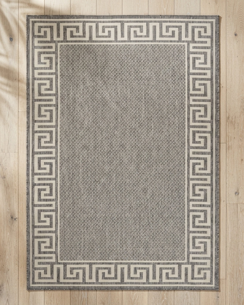 Gray rug with a Greek key border on a wooden floor
