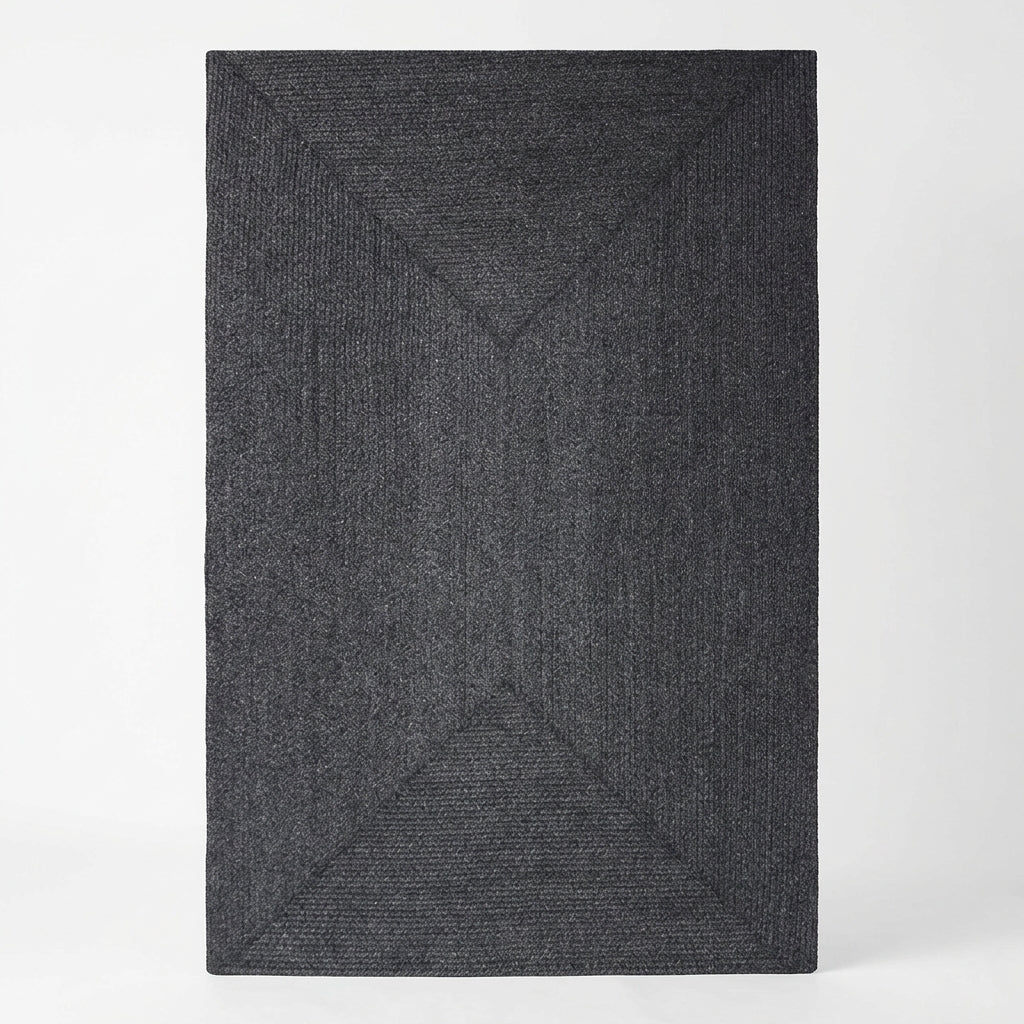 A dark charcoal gray textured area rug with a raised geometric diamond pattern, shown from a top-down perspective on a light gray background.