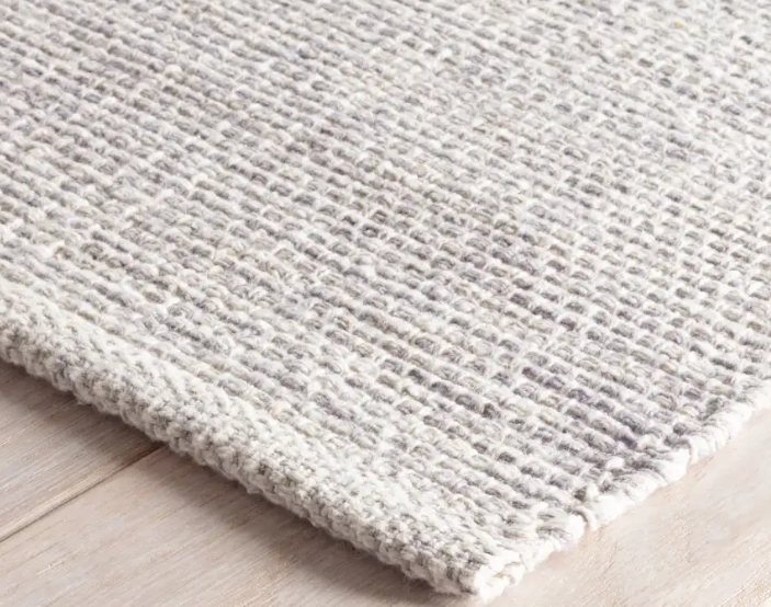 Close-up of a textured gray rug on a light wooden floor