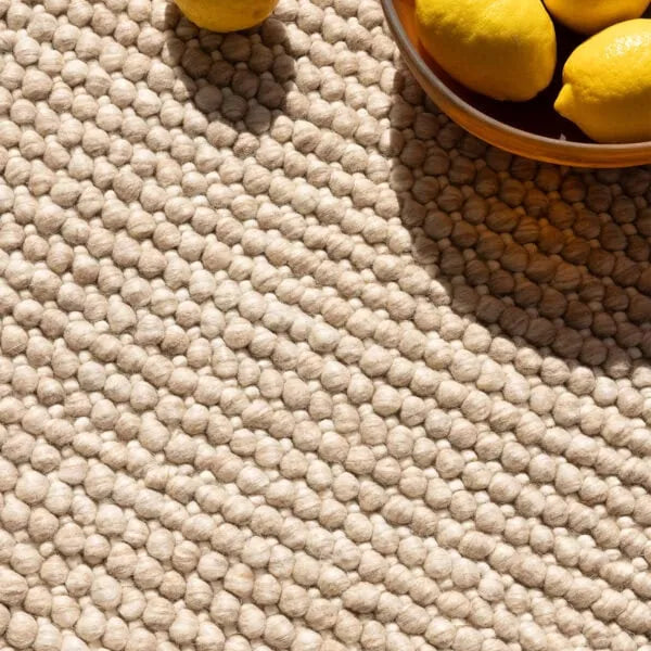 Beige textured rug with lemons on and around it