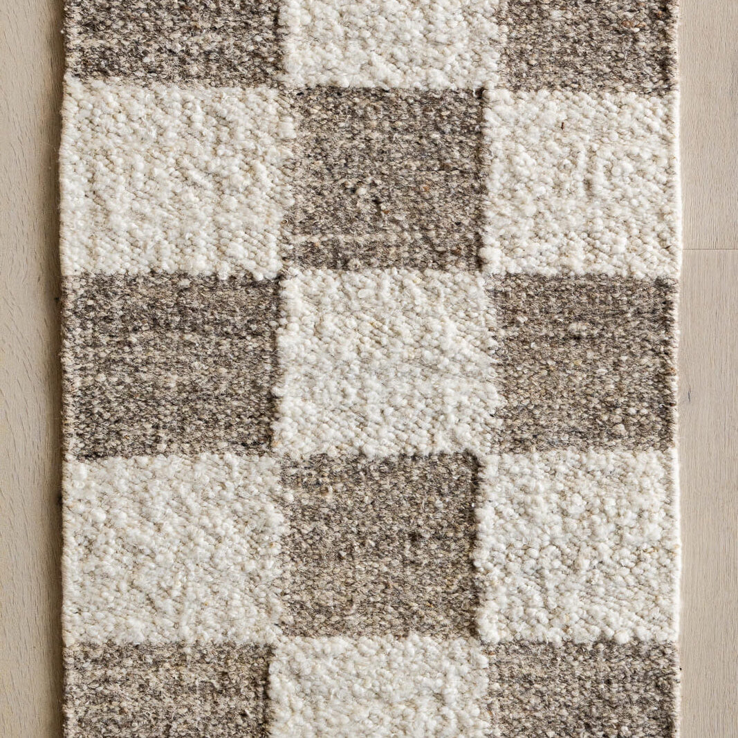 Checkered pattern rug with brown and white squares on a wooden floor.
