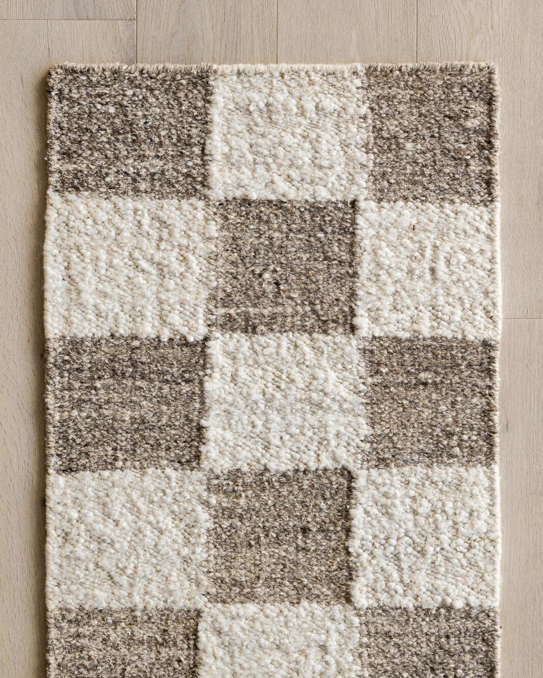 Checkered pattern rug with brown and white squares on a wooden floor.
