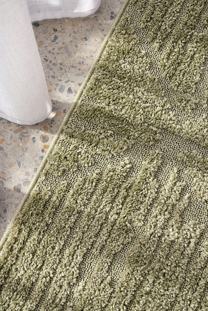 Close-up of a textured green rug on a stone floor.