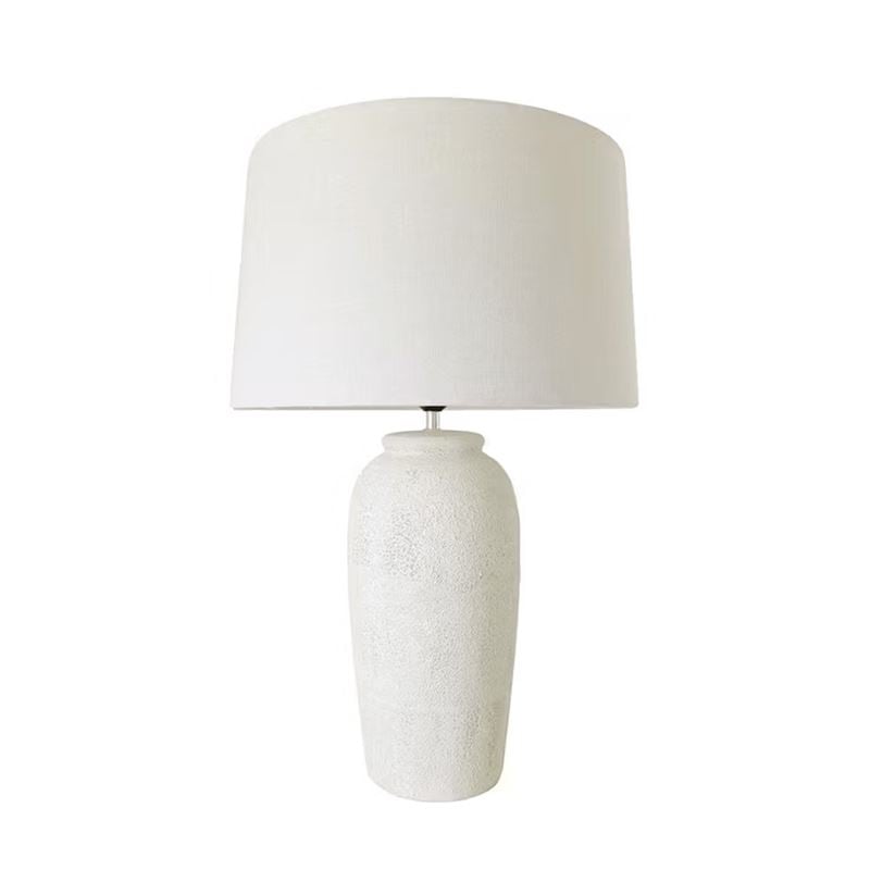 A table lamp with a textured white ceramic base and a matching white fabric drum shade, shown against a plain white background.