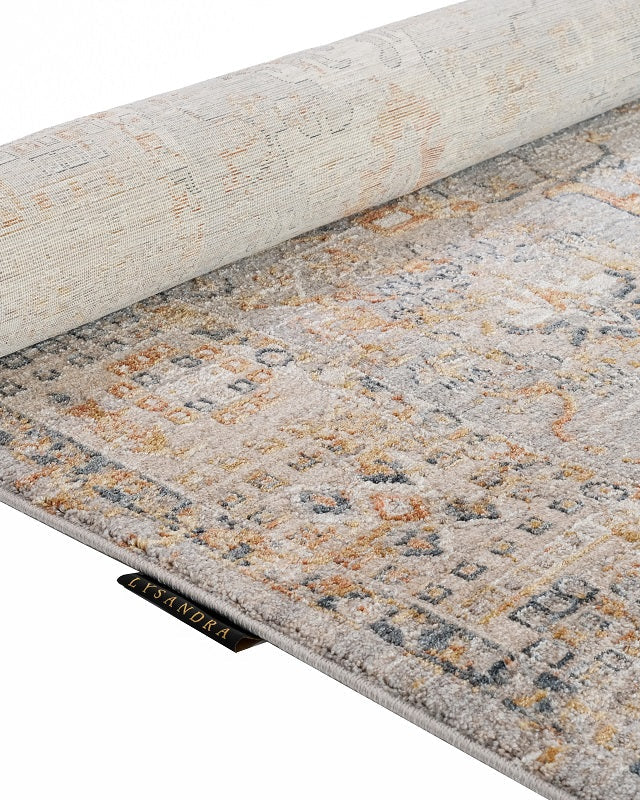 A rolled area rug with a distressed traditional pattern in beige, gray, and muted orange, shown on a clean white background with a black brand tag visible.