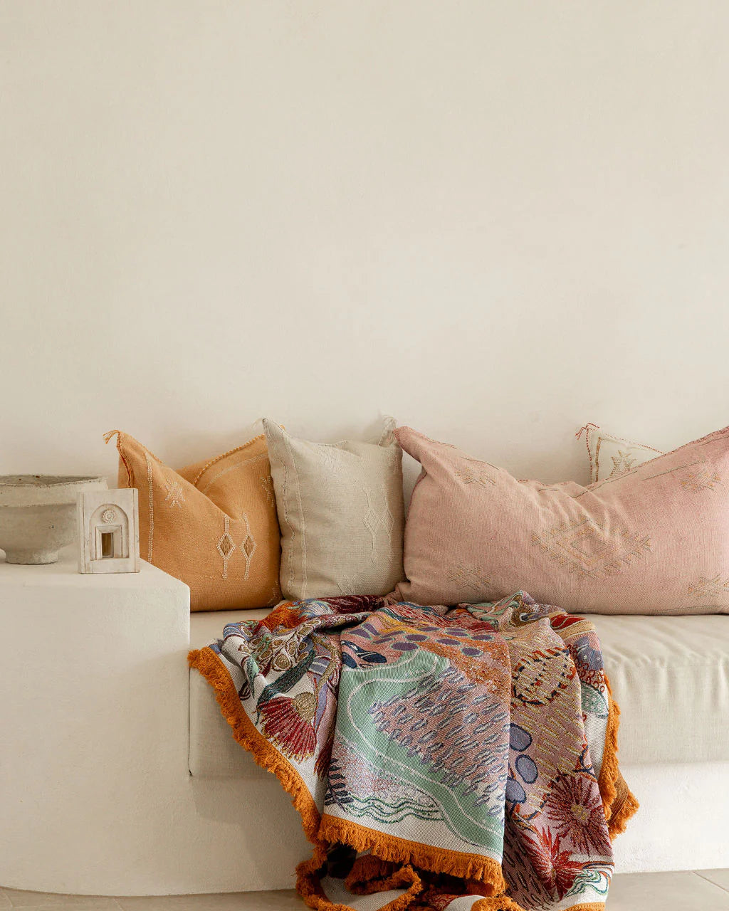 Colorful patterned blanket draped over a white sofa with decorative pillows.