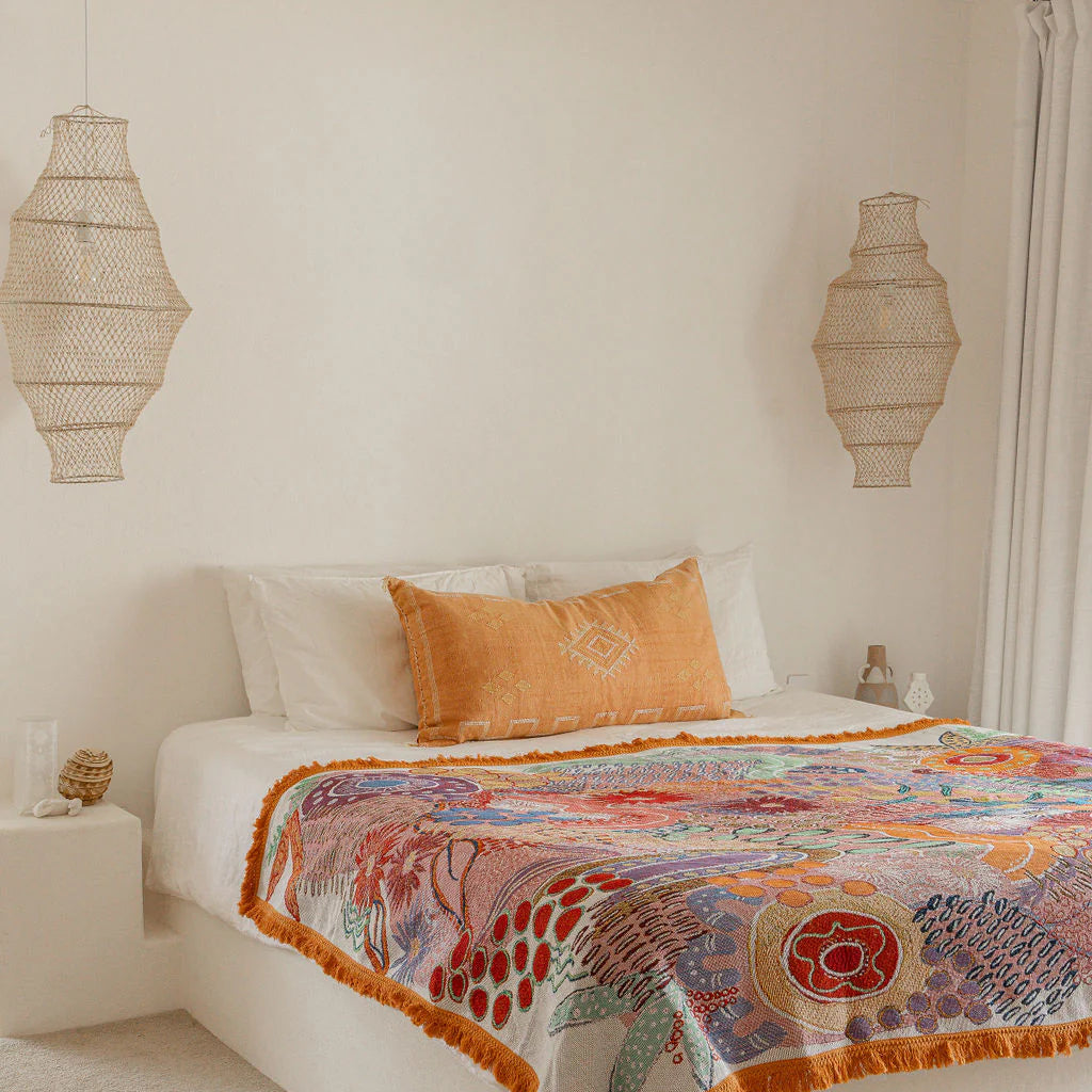 Bedroom with a colorful patterned blanket on a bed, surrounded by decorative lamps and a ceiling fan.