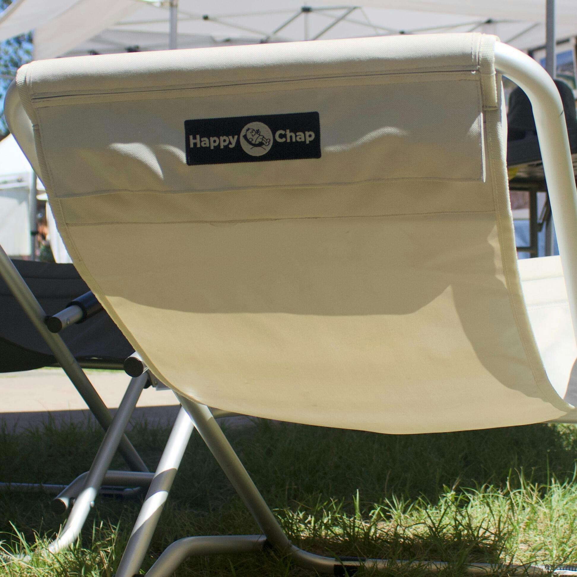 Beige folding chair with 'Happy Chap' logo on a grassy area