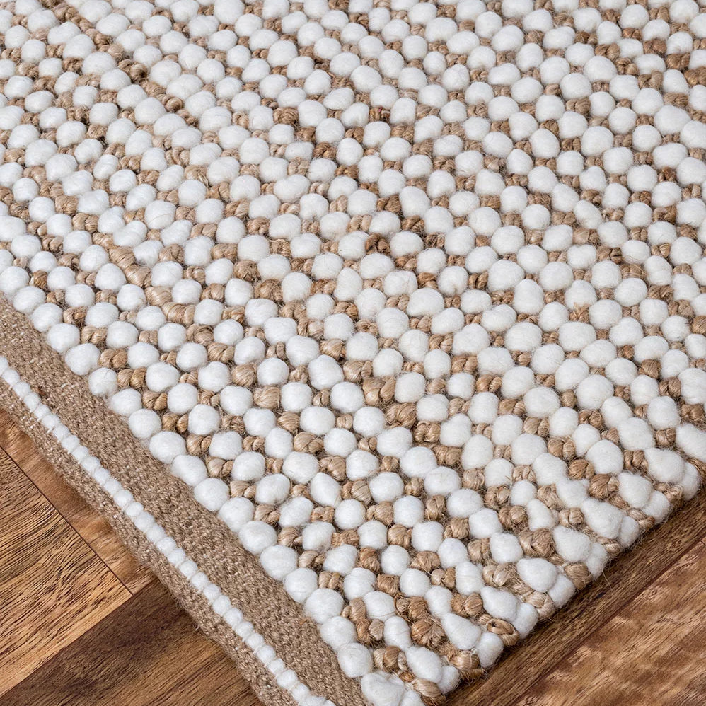 Showcasing the unique blend of wool and jute, this image highlights the rug's intricate texture and the interplay of natural and white colors, emphasising its rustic yet refined look.