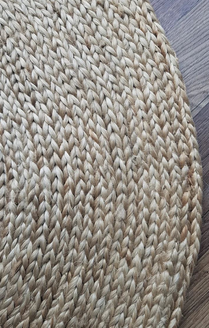 Close-up of a woven beige rug on a wooden floor.