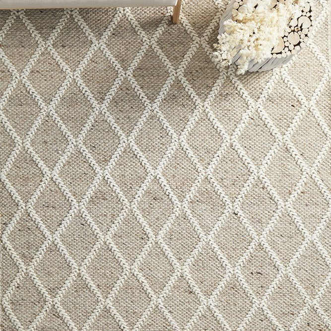 Beige and white diamond patterned rug with a wooden stool and decorative basket on top.