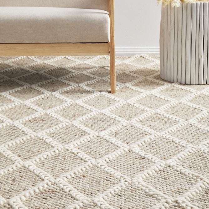 Patterned rug on a floor with a light-colored sofa and decorative item in the background.