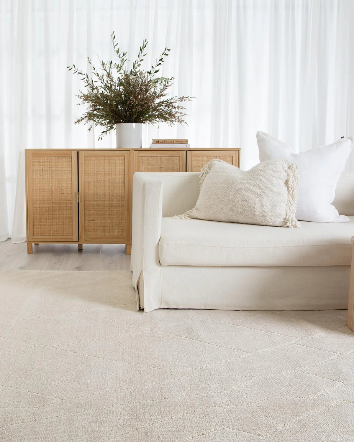 Modern living room with a beige sofa, side table, and decorative cabinet.