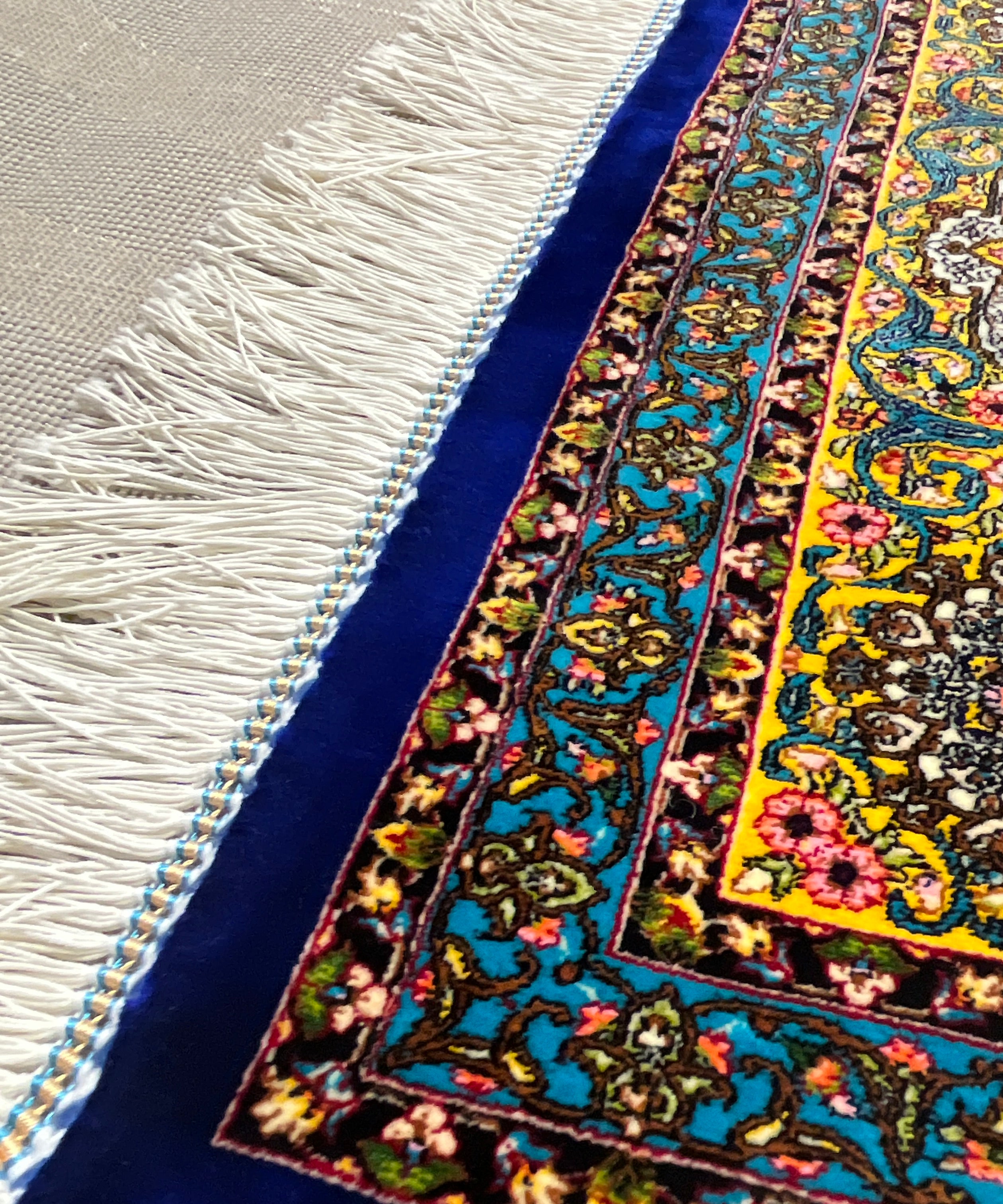 Close-up of a colorful patterned rug with fringes on a neutral background