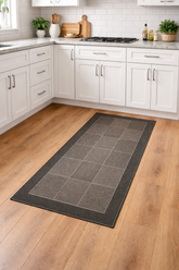Gray checkered kitchen mat on a wooden floor with white cabinets and appliances in the background.
