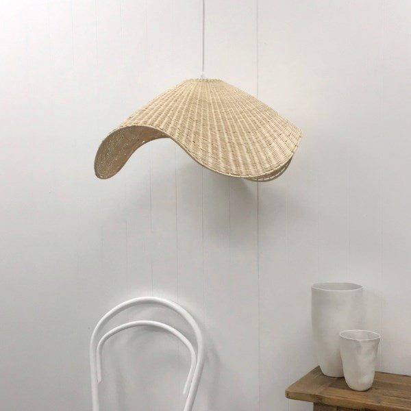 Woven pendant light fixture hanging against a white wall with minimal decor.