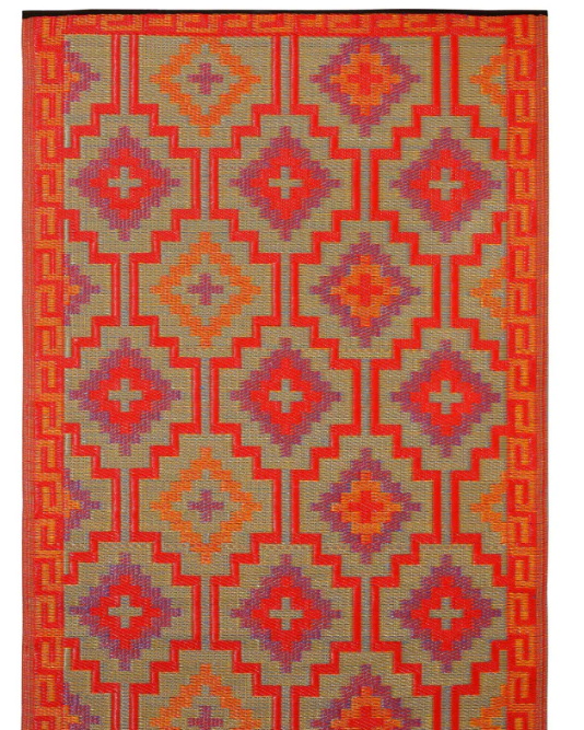 Geometric patterned rug with red, orange, and purple colors on a white background
