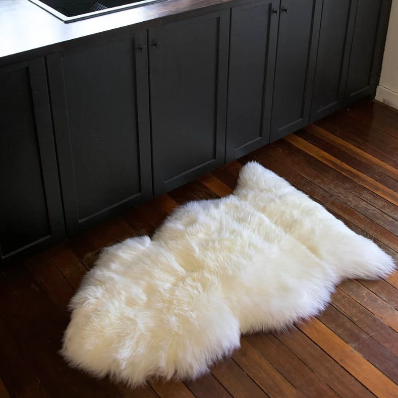White New Zealand wool sheepskin single rug on a wooden floor in a kitchen setting