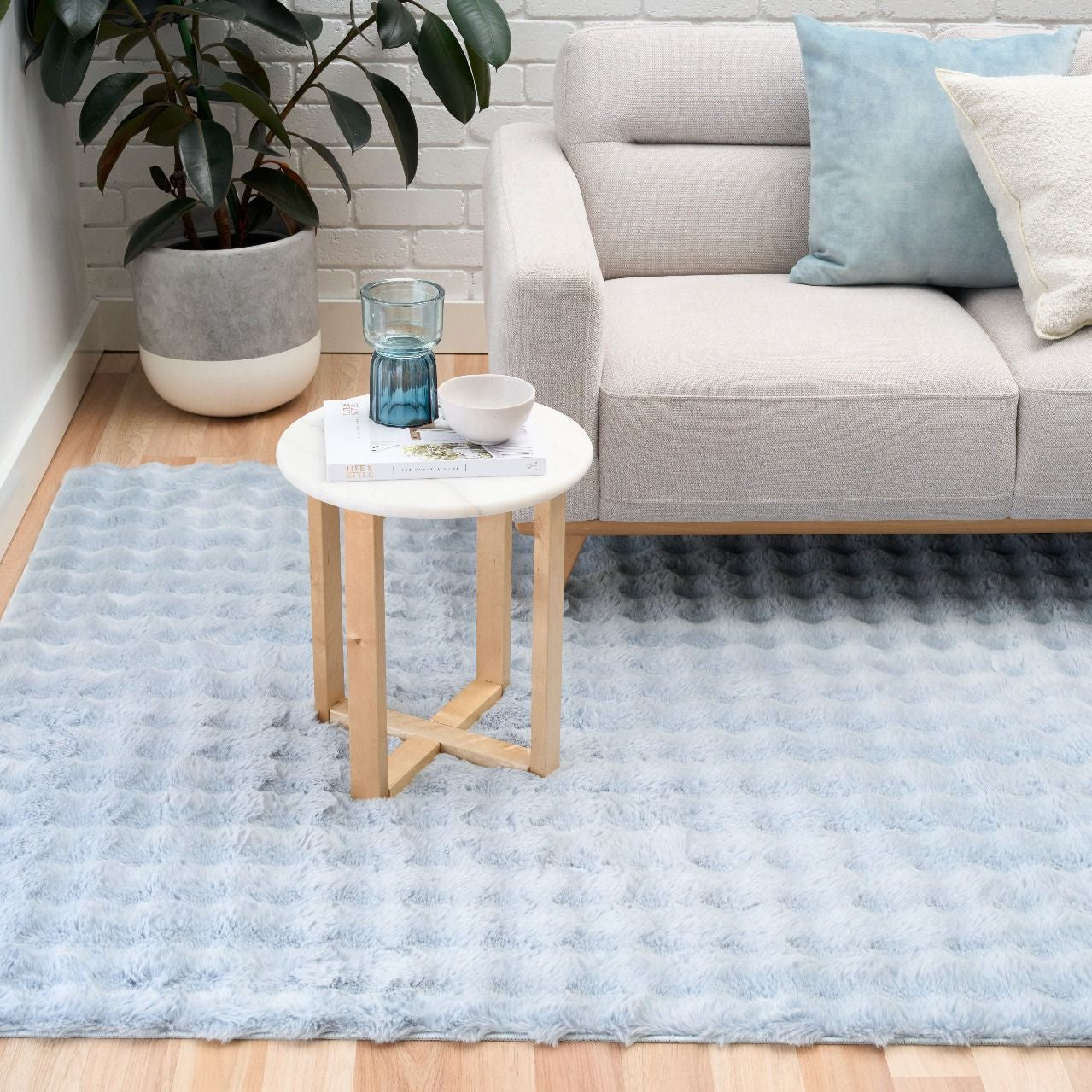 Living room with a light blue rug, gray sofa, and small round table.