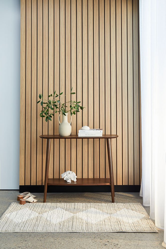 Wooden console table with decorative items against a striped wall.