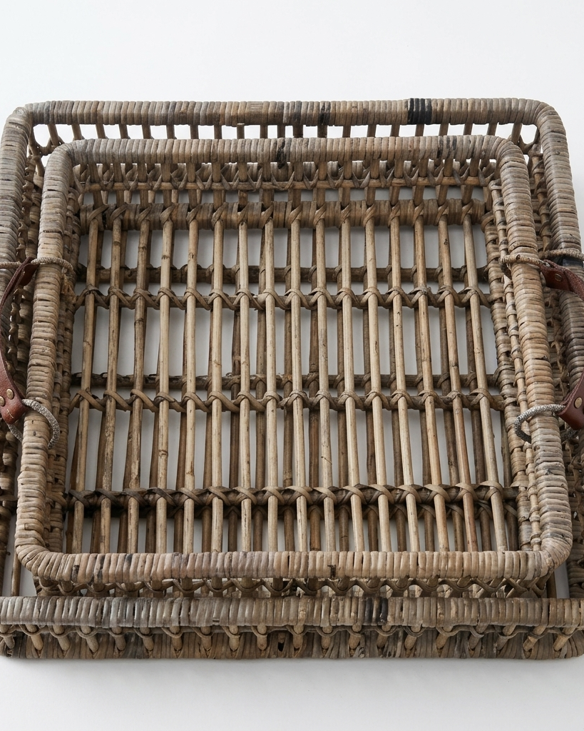 A rectangular woven rattan tray with a natural brown and beige textured body and dark brown leather handles on the sides, photographed from a top-down angle against a plain white background.